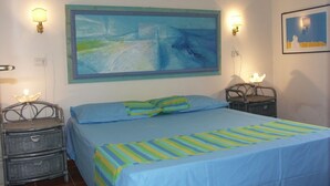Ein Schlafzimmer mit einem Bett, zwei Nachttischen, einem Gemälde und einer Wandlampe.