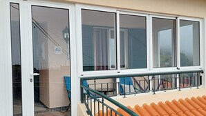A covered outdoor area with a tiled floor, a metal railing, and a sliding glass door leading to an interior space. - Viewpoint House (Ponta Sol)