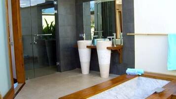 Enjoy a refreshing shower in the bathroom, featuring a large mirror, pedestal sinks, and a glass shower enclosure.