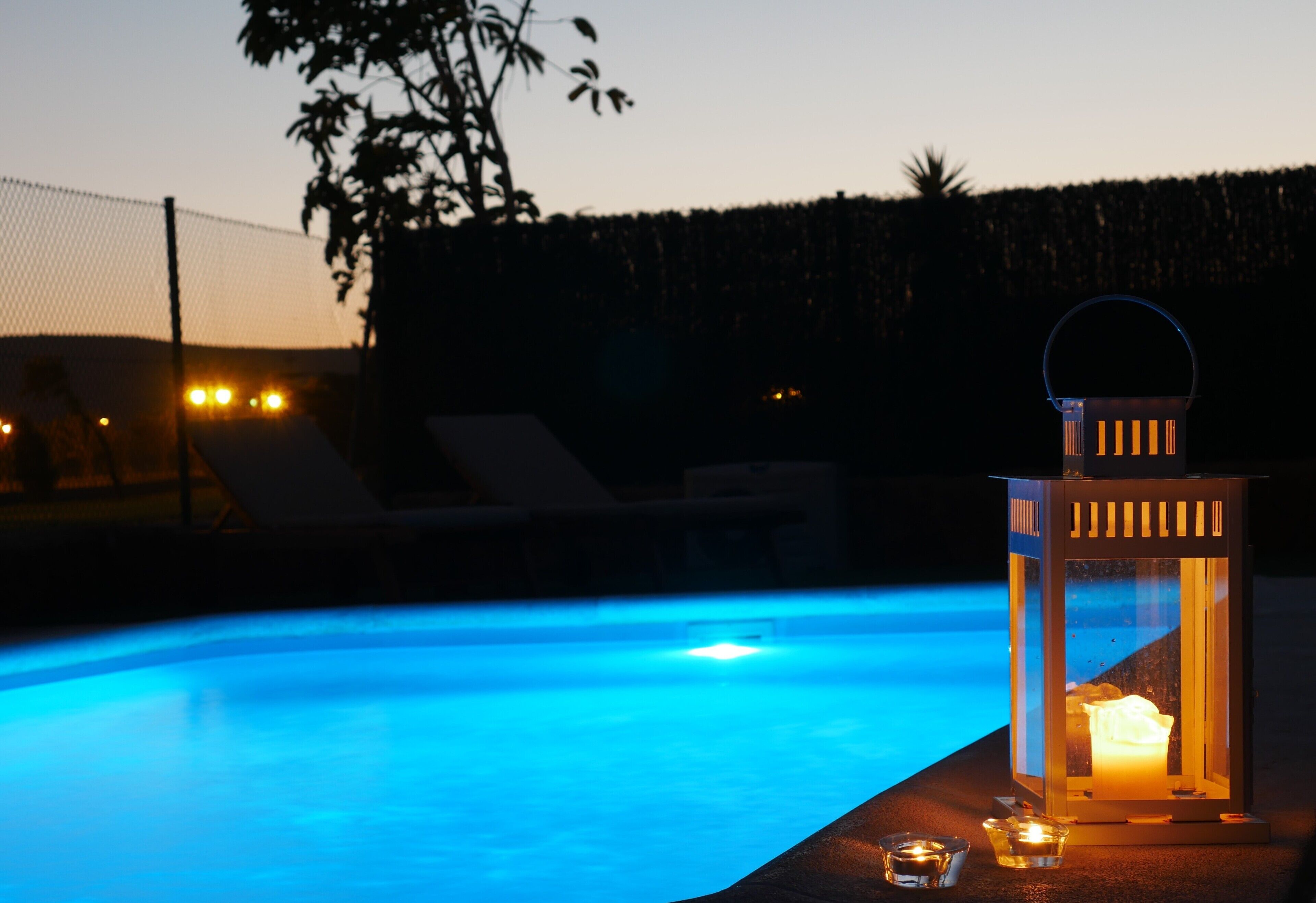 A swimming pool with a lantern and candle on the edge.