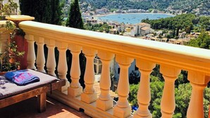 Un balcone con vista su una cittadina costiera e montagne.