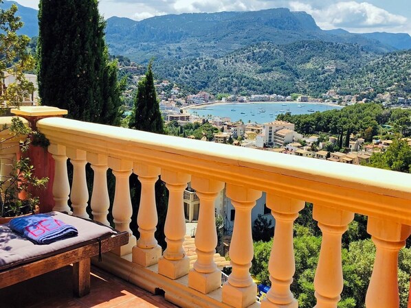 A balcony with a view of a coastal town and mountains.