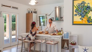 Een moderne keuken met een centraal eiland, barkrukken en een eethoek.