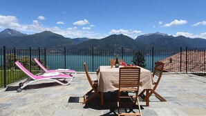 A terrace with a table and chairs overlooking a lake and mountains. - Parco dei Cervi Terrazzo, Plesio, Italy (Plesio)