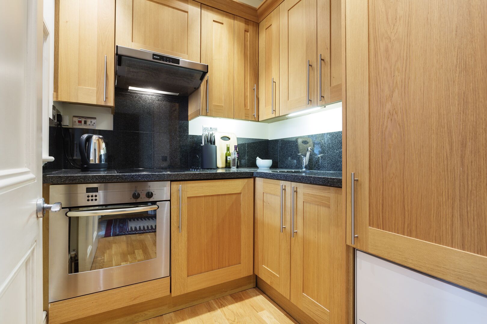 A kitchen with wooden cabinets, a stainless steel oven, and a black countertop.