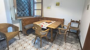 A dining area with a wooden table, chairs, a bench, and a window with a metal grille. - Villa Maria lake view, terrace, parking, garage, 7minutes walk to the village. (Verona)