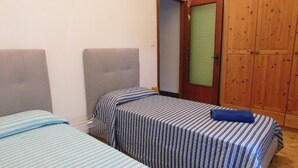 A bedroom with two beds, a wooden wardrobe, and a door with a frosted glass panel. - Villa Maria lake view, terrace, parking, garage, 7minutes walk to the village. (Verona)