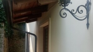 A narrow outdoor corridor with a wooden ceiling, a stone wall on one side, and a door at the end. - Villa Maria lake view, terrace, parking, garage, 7minutes walk to the village. (Verona)