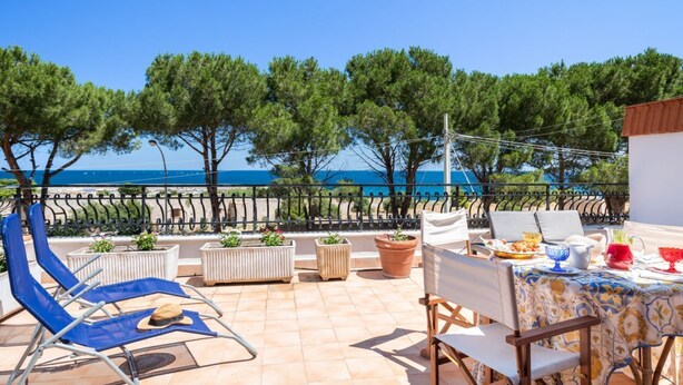 A terrace with outdoor seating, a table set for dining, and a view of the sea. - Domus Sicily - Il nido di suerte sea view (Palermo)