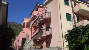 Un edificio rosa de varios pisos con una escalera en espiral, escalones de piedra y un cielo despejado.