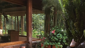 Two children in a hot tub surrounded by lush greenery and a rustic wooden structure.
