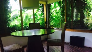 A round table with a dark tablecloth, two wicker chairs, and a lamp.