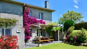 A stone building with a covered patio, outdoor seating, and lush greenery. - Perfectly located summer cottage, just a stone's throw from 5 pristine beaches! (Ortigueira)