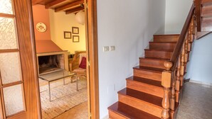A wooden staircase with a glass railing leading to a living room area with a fireplace. - Perfectly located summer cottage, just a stone's throw from 5 pristine beaches! (Ortigueira)