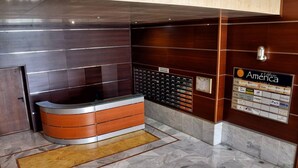 Un área de recepción con un mostrador curvo de madera, piso de mármol y un directorio en la pared.