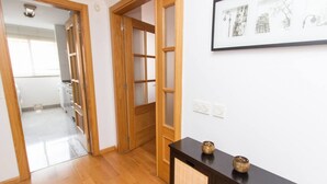 Un pasillo con puertas de madera, una consola oscura con dos objetos decorativos y un cuadro en la pared.