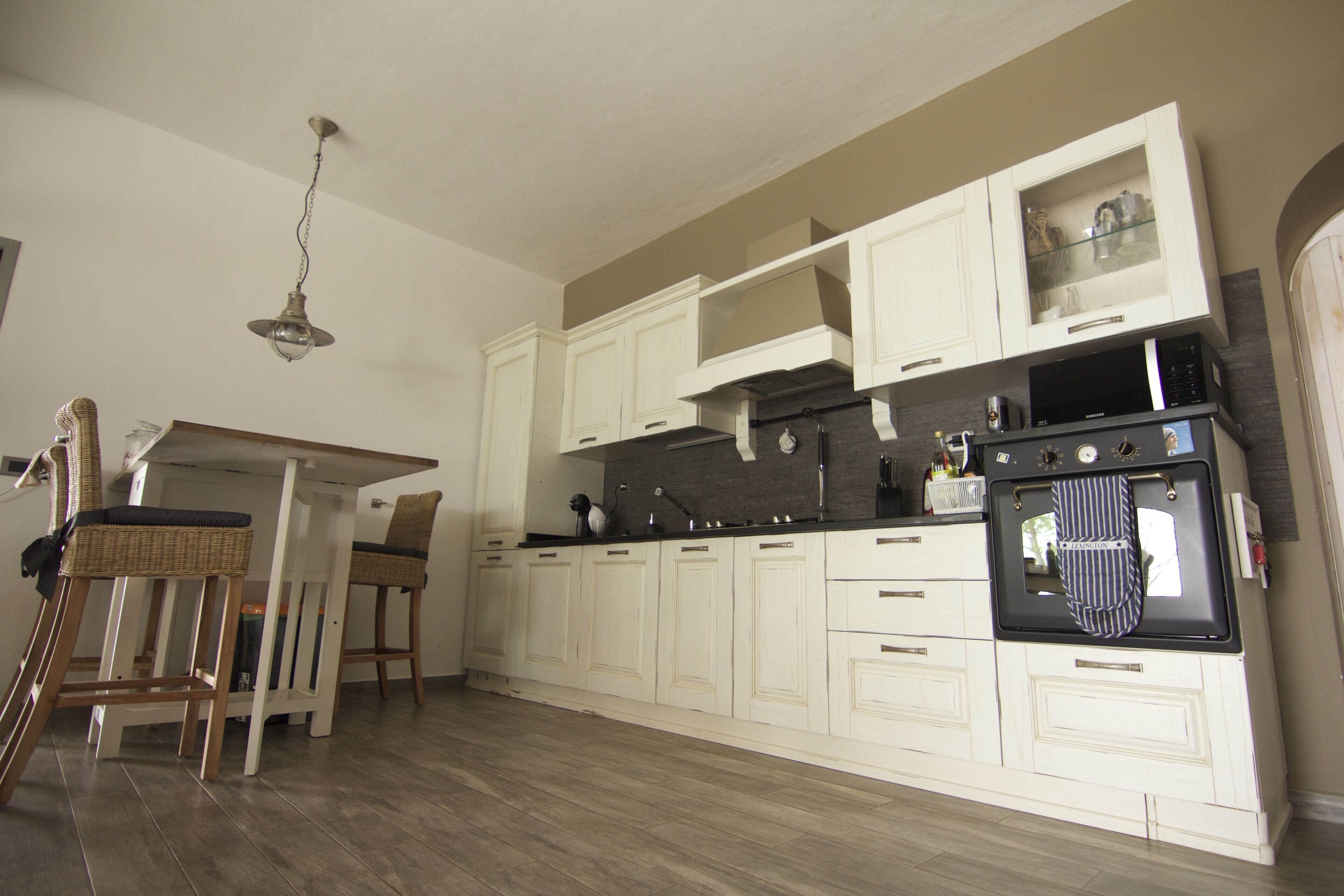A kitchen with white cabinetry, a dining table with chairs, and a hanging light fixture.