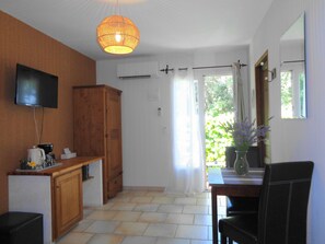 A kitchen with a wooden cabinet, a television mounted on the wall, a hanging light fixture, and a window with curtains. - Bed & Breakfast in a Farmhouse- air conditionned - Lacoste (Lacoste)
