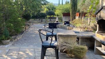 Un espace patio avec des sièges d’extérieur, une table en pierre et un barbecue.