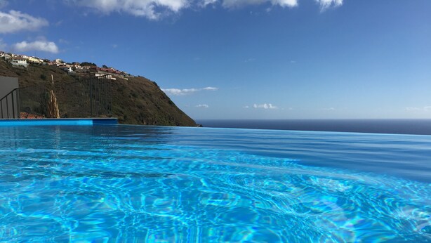 A clear blue pool with a view of a hillside and ocean in the background. - Syso House - Extraordinary ocean view ----- (New Promotions) ----- (Arco da Calheta)