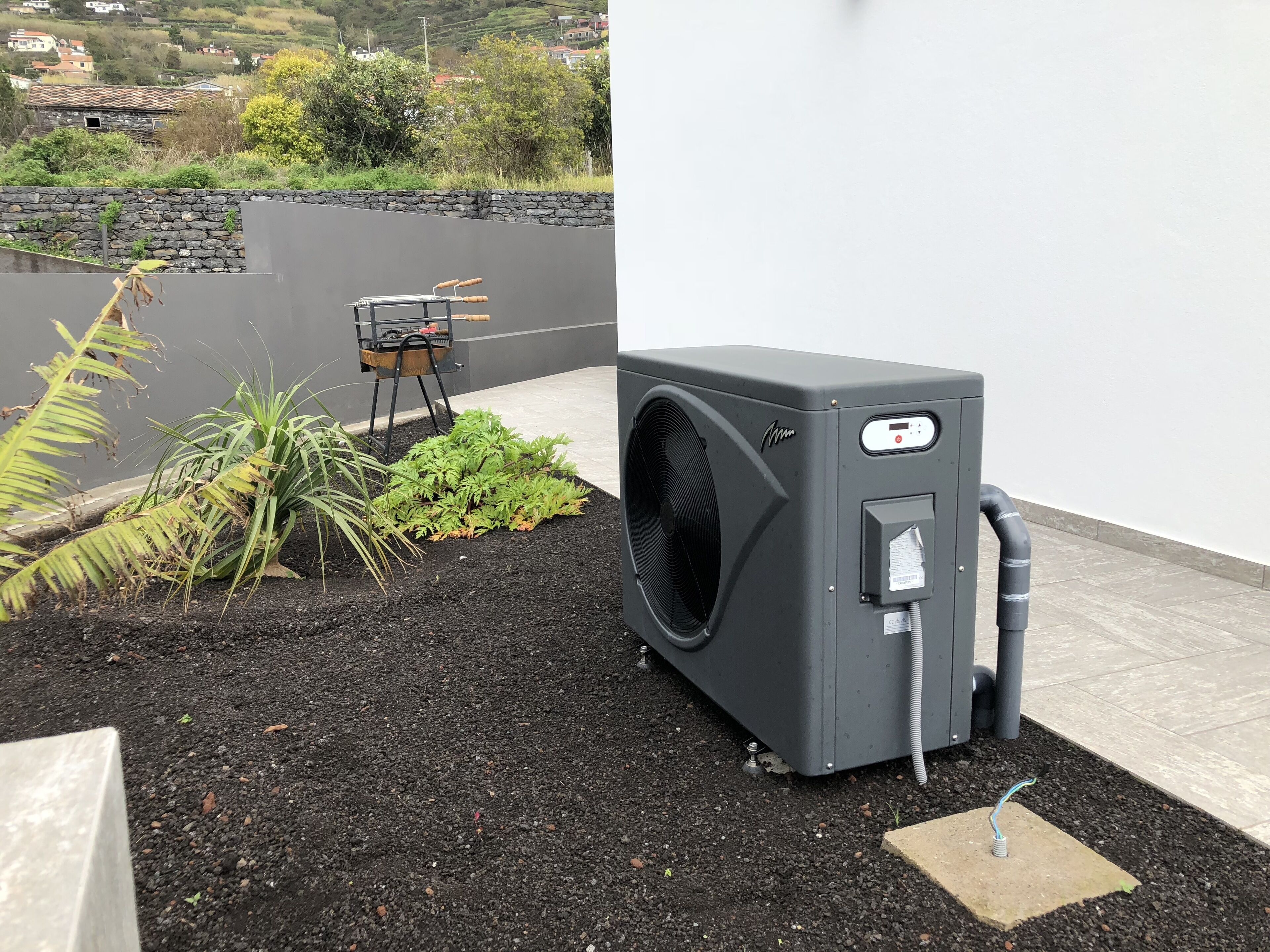 A compact, gray outdoor unit with a digital display, connected to a flexible hose, and a power cord.