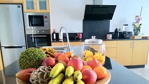 A kitchen counter with a fruit bowl containing bananas, apples, and pomegranates. - Syso House - Extraordinary ocean view ----- (New Promotions) ----- (Arco da Calheta)