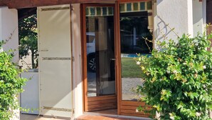 A wooden door with a glass panel, a white wall, and a tiled roof. - Single-storey house, rated 4*, air-conditioned, private pool. 10 minutes from the sea. (La Colle-Sur-Loup)