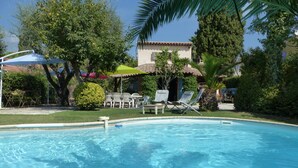 A swimming pool with clear water, surrounded by lounge chairs and umbrellas, with trees and a building in the background. - Single-storey house, rated 4*, air-conditioned, private pool. 10 minutes from the sea. (La Colle-Sur-Loup)