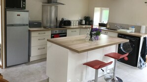 Cozinha moderna com ilha central, eletrodomésticos de aço inoxidável e máquina de lavar louça.