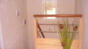 A wooden bench with a metal frame, a glass window, and a vase with green plants and nuts. - New holiday house 100 meters from the sea (Kerlouan)
