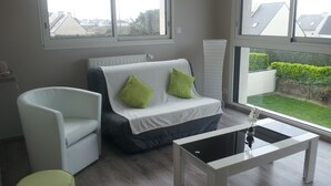 A modern living room with a grey sofa, a white armchair, and a glass coffee table. - New holiday house 100 meters from the sea (Kerlouan)