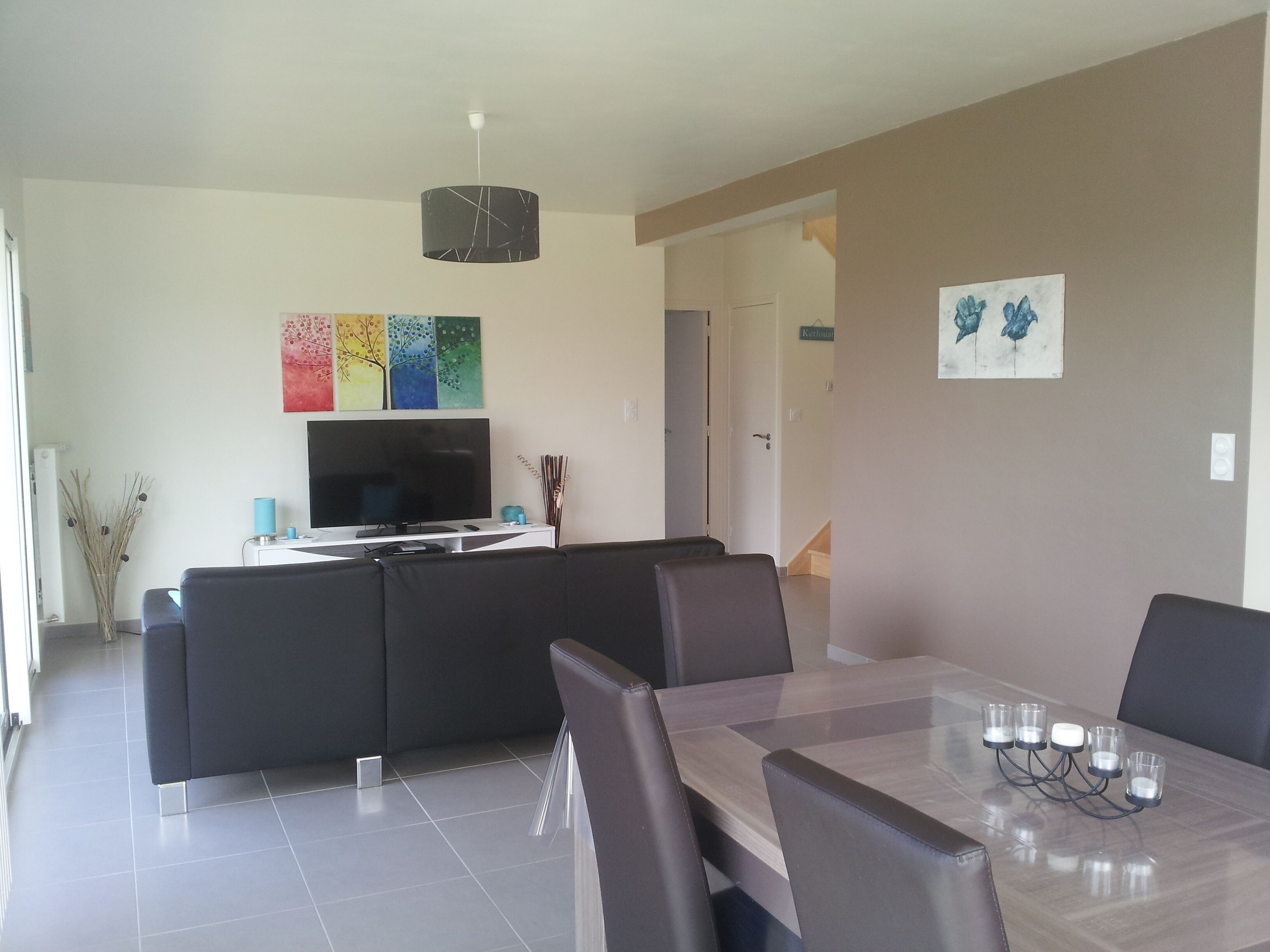 Un salon moderne avec un téléviseur, un canapé et une table à manger.