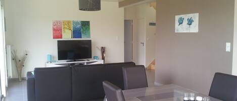 Un salon moderne avec un téléviseur, un canapé et une table à manger.