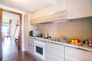 Une cuisine moderne équipée d’un four encastré, d’un four à micro-ondes et d’un évier en acier inoxydable.