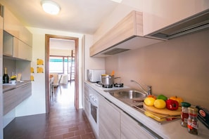 Een moderne keuken met een fornuis, spoelbak en diverse soorten fruit en groenten op het aanrecht.