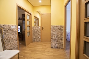 Un couloir doté d’un plancher en bois, agrémenté d’éléments en pierre et muni d’une porte en bois.