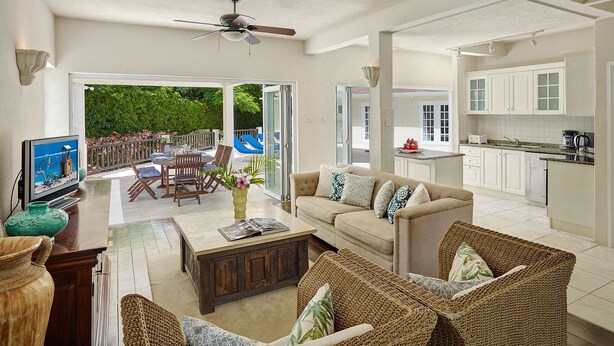 A spacious living area with a sofa, coffee table, and wicker chairs. A television is on a stand, and a ceiling fan is visible. - Luxury 6 Bed Villa With Pool, Mullins Bay (Mullins)