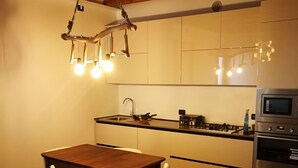 A modern kitchen with white cabinets, a wooden dining table, and a built-in oven.