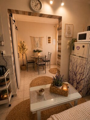 A cozy kitchen with a microwave, a clock, and a dining area with a table and chairs.