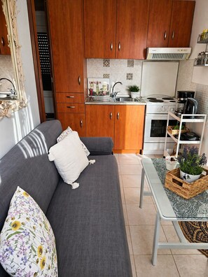 A compact kitchen with wooden cabinets, a built-in stove, and a small dining area with a table and bench.