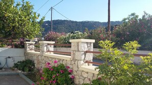A stone wall with a metal railing, surrounded by flowering plants and greenery.