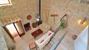 A stone-walled living room with a sofa, coffee table, and a hanging light fixture.