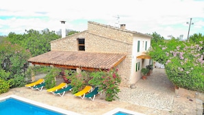 A stone building with a swimming pool, outdoor seating, and potted plants.