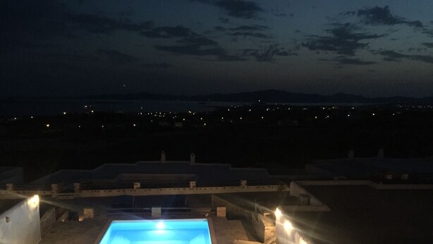 A swimming pool with a view of distant city lights at night. - Villa Meraki (Agkeria)