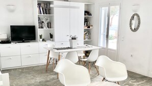 A modern, well-lit room with a flat-screen TV, white furniture, and a stone-tiled floor. - Villa Meraki (Agkeria)