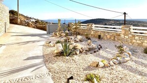 A paved pathway leading to a stone wall with a view of the sea and hills. - Villa Meraki (Agkeria)