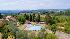 Una villa con piscina, rodeada de vegetación exuberante y montañas al fondo.