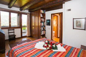 A bedroom with a bed, a bookshelf, a window, and a door. - Villa Il Castagno, Cerano d'Intelvi, Italy (Cerano d'Intelvi)
