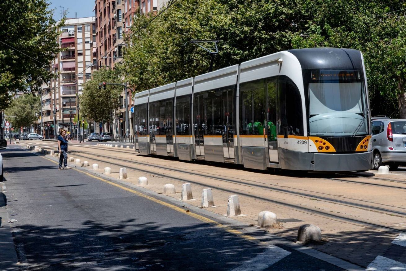 A modern tram on a city street with buildings and trees in the background.