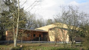 A modern building with a wooden exterior near a body of water. - Au Bas Chalonge Gite in Ligné (Ligné)